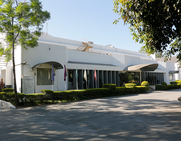 Exterior of a large industrial warehouse with a windsock on the roof