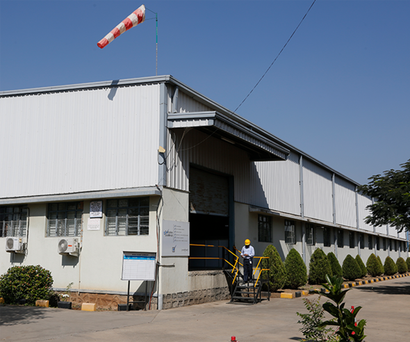 Exterior of a large industrial warehouse with a windsock on the roof