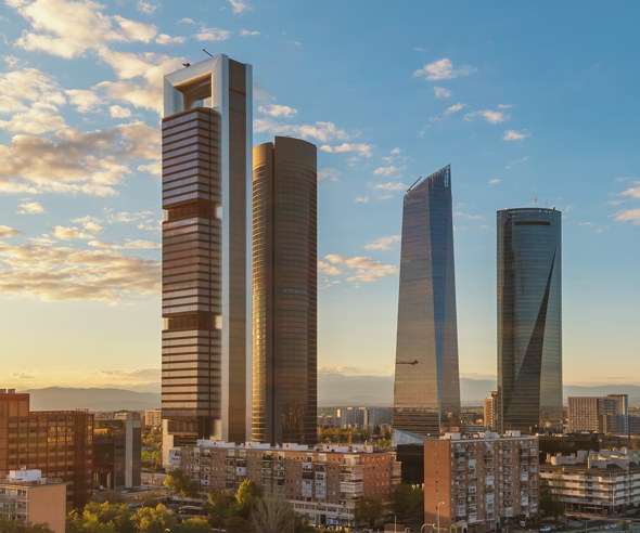 Four iconic skyscrapers above surrounding residential buildings under a partly cloudy sky