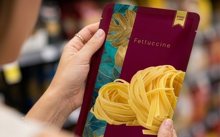 Woman holding pasta packaging in the supermarket aisle