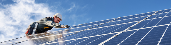Technician installing solar panels on a rooftop, illustrating renewable energy and climate action.