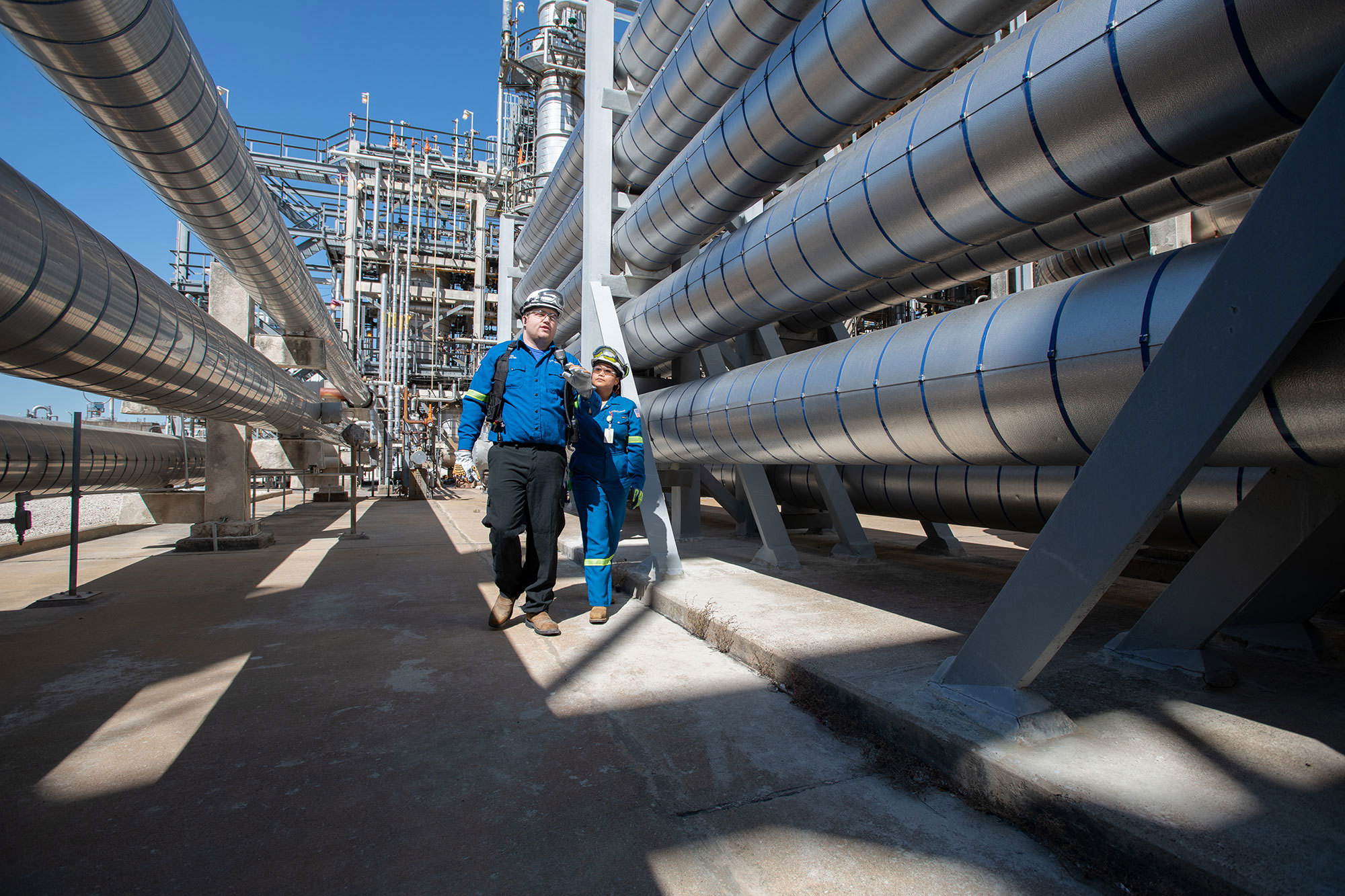LYB employees walking through a facility between large pipelines.