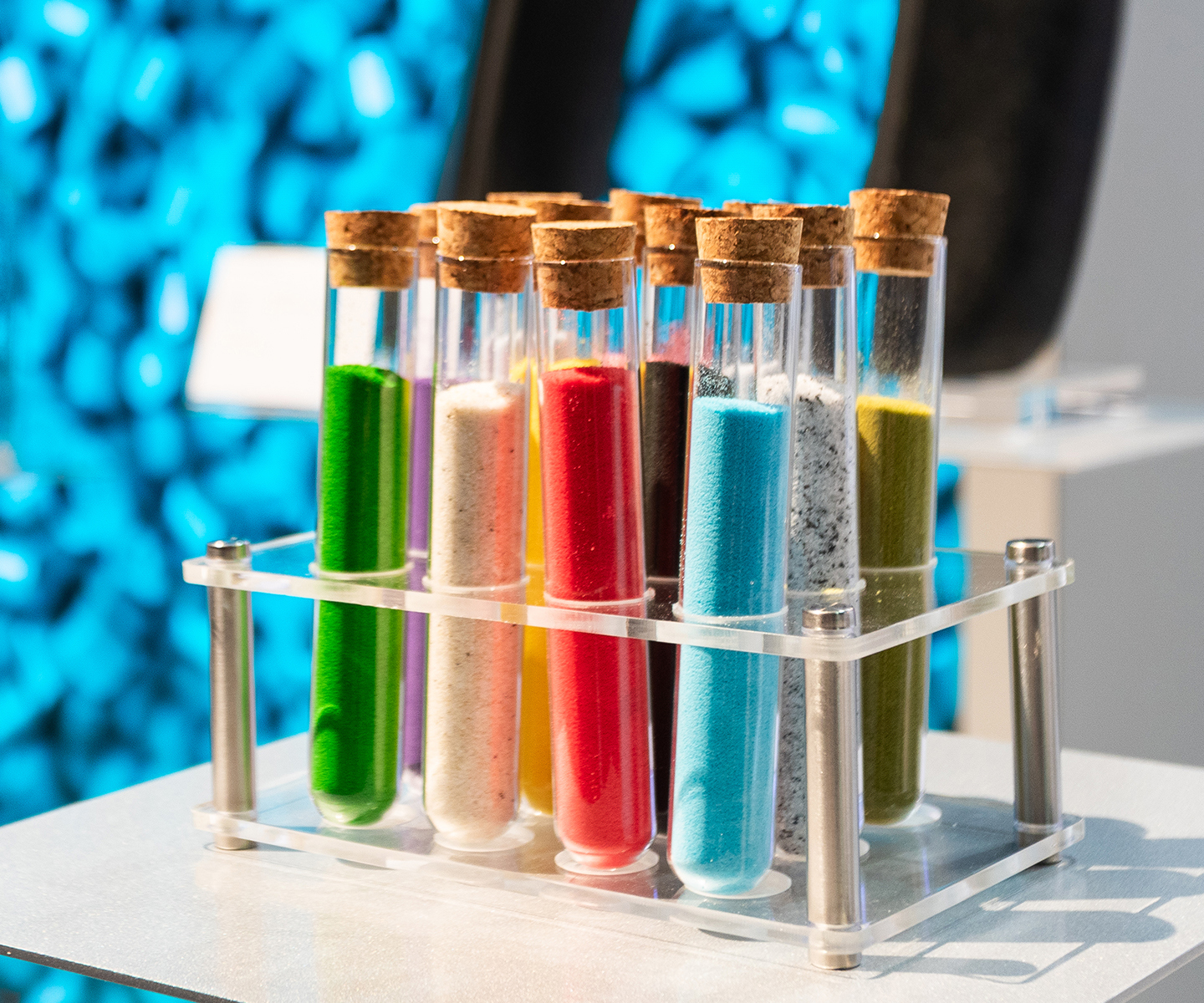 A display of small glass containers filled with colorful LYB materials on a table at a trade show.